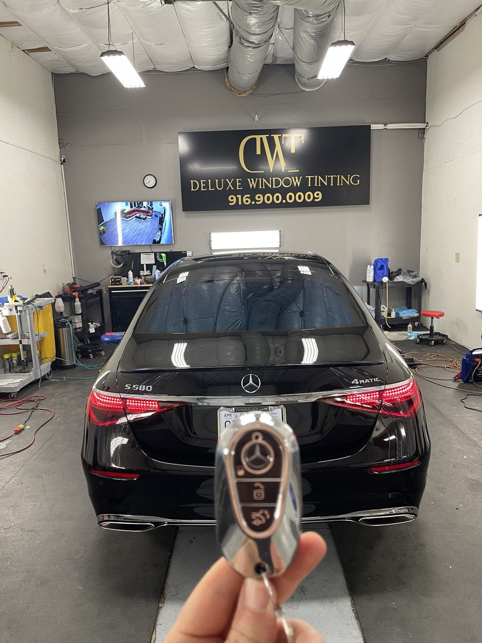 Rear view of a black Mercedes S580 with tinted windows in a professional tint shop.