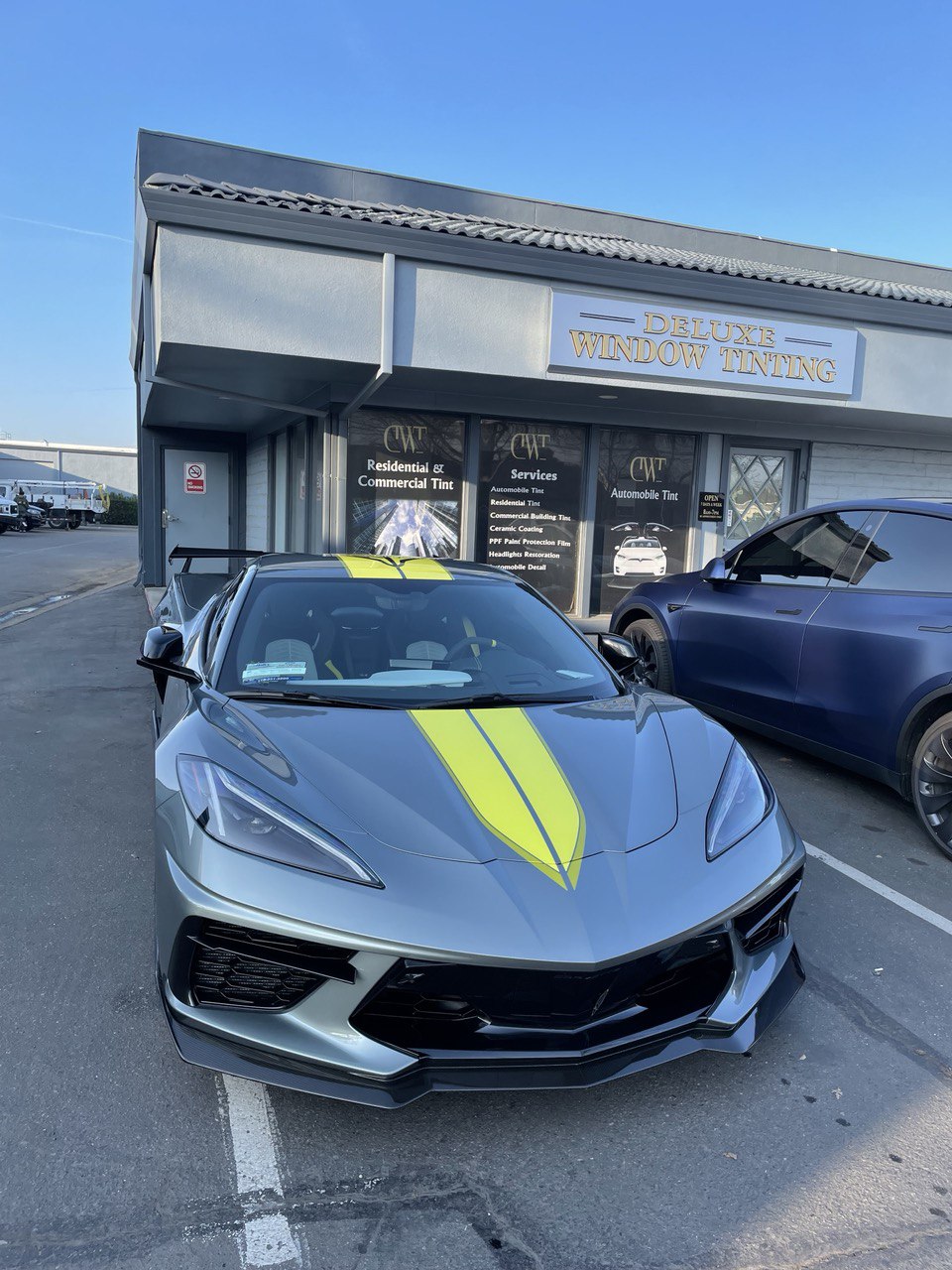 Grey Corvette C8 with yellow stripes parked in front of Deluxe Window Tinting shop in Gold River.